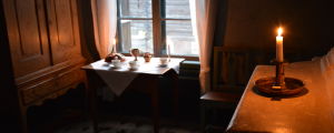 Murarens hem i Klosterbackens hantverksmuseum. Ett ljus brinner i ett av stugorna i Klosterbacken.