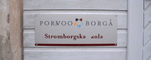 Skolans skylt är sliten och symboliserar väl skolbyggnadens skick. Skylt med texten Stromborgska kola.