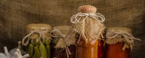 Odlarna borde göra tomatsås av sina produkter, föreslår en läsare. Hemgjord tomatsås i glasburk. I bakgrunden andra inlagda grönsaker och färska tomater och vitlök.