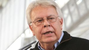 harmaapäinen mies katsoo vähn sivulle