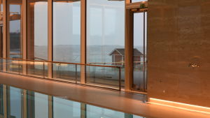 Utanför bassängområdet breder en stor terrass ut sig med utsikt över havet. utsikt genom glasfönster mot havet