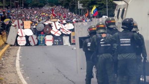 Demonstranterna blockerade en central motorväg i Caracas och drabbade samman med polis. Demonstrationer ordnades på flera håll i landet. Polis med kravallsköldar och vattenkanoner står mittemot tusentals demonstranter som söker skydd bakom fanersköldar på en motorväg i Caracas.