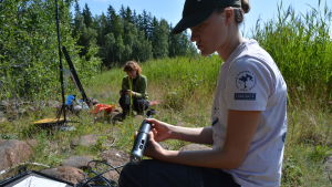 Roosa Mikkola och Ella Pippingsköld. Roosa Mikkola visar upp en av de många utrustningar som hon och Ella Pippingsköld har med sig. Saken som Mikkola har i handen mäter de flesta värden man kan ta av ett vattendrag.