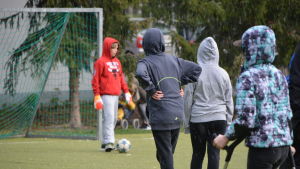 Mitt i allt kommer det en hagelskur, men då är det bara att lyfta upp huvan. Vårberga skolas elever spelar fotboll i en hagelskur.