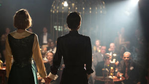 Kate (Lily-Rose Depp) och Laura (Natalie Portman) står på scenen, ser ut över publiken och håller varandra i handen.