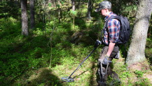 Joel Jokelainen letar efter tydliga tecken på det förflutna med sin nya metalldetektor. Joel Jokelainen med metalldetektor i skogen