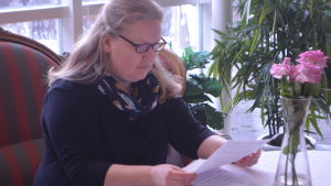 Monica Björkell-Ruhl har fått plöja igenom många dokument för att hitta rätt i bidragsdjungeln. Hon upplever inte att staden stöder hjälpsökande i deras processer, snarare tvärtom. En kvinna sitter vid ett bord och läser koncentrerat ett papper. Framför henne på bordet ligger fler papper.