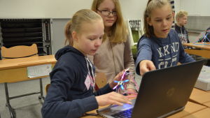 Sara Laihinen, Frida Balthasar och Tilda Lindroos använder datorn för att koda en robot. Tre flickor jobbar framför en dator.