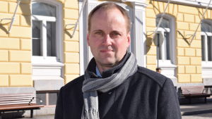 Stadsdirektör och blivande förlags-vd Tom Simola. En man i halsduk och jacka står utanför stadshuset i Ekenäs. Raseborgs stadsdirektör Tom Simola.