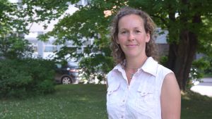 Emilia Horttanainen har arbetat mycket med planering och projekt som berör landskapsarkitektur. Kvinna med lockigt hår och rosa topp står i en park. I bakgrunden. syns träd och en gata.