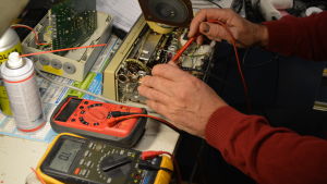 En gammal radio får nytt liv. Reparatören mäter komponenter i en gammal radio