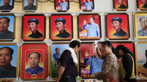 Besökare tittar på souvenirer framför en vägg med porträtt av Mao Zedong i Shaoshan i Hunanprovinsen i Kina. Shaoshan var Maos hemstad. Besökare tittar på souvenirer framför en vägg med porträtt av Mao Zedong i Shaoshan i Hunanprovinsen i Kina. Shaoshan var Maos hemstad.
