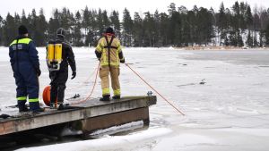 En dykare på bryggan, en i vattnet. I Finlands grumliga vatten behövs ett rep för att hitta tillbaka till ytan - speciellt om hålet i isen är litet. Räddningsverket i östra nyland övnings dyker under ytan på vintern