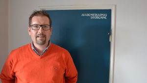 Patrik Fellman framför en dörr som visar att Akademifruarnas Syförening varit med i finansieringen 1950. Patrik Fellman.