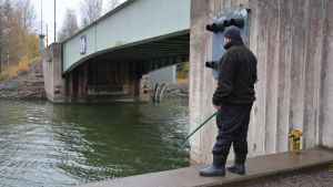 Fiskarna vid Strömma kanal störs inte av tidvattnet, men när strömmen byter riktning skräms strömmingen bort, säger de. En fiskare vid Strömma kanal håller i ett metspö.