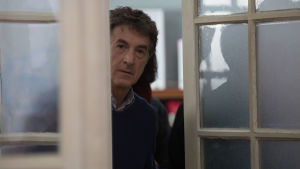 Nästa! säger läkaren Jean Pierre (François Cluzet ) i fimen Médecin de campagne. Skådespelaren François Cluzet kikar ut genom en dörrspringa i filmen Médecin de campagne