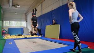Trampolinen välkomnas av Piffens gymnaster. Flicka gör volt på trampolin under gymnastiklektion.