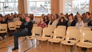 En massa elever sitter på stolar i festsalen i Karis-Billnäs gymnasium och lyssnar på föredrag om Finland 100 år.