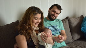 Paret Nour och Shfan sitter i soffan med sin dotter Lara i famnen.