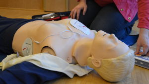 Nu kan hjälpen nå mycket snabbare. Kvinna visar hur en defibrillator fungerar.
