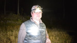 Tommy Arfman gör sig redo att följa efter ut i skogen. Jägare med pannlampa i mörk skog.