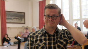 Sam Sihvonen spelar huvudrollen och gör grafiken för årets pjäs. Sam Sihvonen i Teaterboulaget med kollegor i bakgrundden