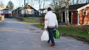 Vissa kan behöva hjälp med att handla eller bära hem sina matkassar. Man bär på två EU-matkassar.