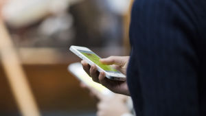 En app för färdtjänsten ska hjälpa vid beställningen. I appen har klienterna egen profil så färdcentralen vet vilken typ av bil och assistans som kan behövas. Bildsättningsbild. en person håller i en mobiltelefon