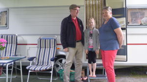 Taisto, Seelia och Marina Lahtinen bor en vecka på Ekenäs camping. Ett par med sitt barnbarn står på trappan till sin husvagn.