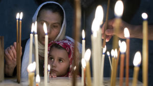 Kvinna och flicka tänder ljus i Jerusalem på söndagen efter påsk. A child with her mother light candles in a chapel in the Church of the Holy Sepulchre in Jerusalem's Old City on Easter Sunday, 20 April 2014. The church is the accepted site of Jesus Christ's crucifixion, burial and resurrection.