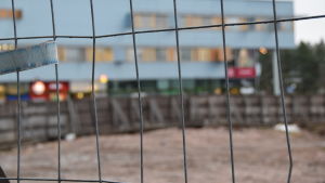 Byggarbetet i centrum har stått stilla länge, men nu har ett besvär gällande parkeringsplatsen dragits bort från Högsta Förvaltningsdomstolen och arbetet kan fortskrida. Galler framför byggarbetsplats, i bakgrunden Grankulla köpcentrum.
