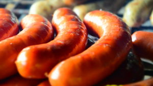 Korv är en tradition under hogswatch. Tre stycken grillkorvar i närbild, i bakgrunden syns ytterligare korvar. De ligger alla på en grill.