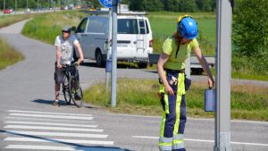 Aija Pelkonen från Borgå stad byter ut en komponent i trafikljusen. En kvinna reparerar trafikljusen vid ett övergångsställe.