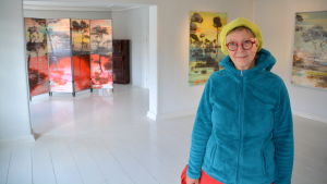 Bildkonstnär Ylva Holländer. I bakgrunden verk av Ulla Repo. Ylva Holländer i gamla kaplansgården