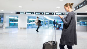 I framtiden beställer du buss via telefonen. Kvinna på flygfält som petar på sin telefon.