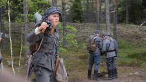 Määttä (David Sandqvist) med ett vapen på axeln i pjäsen Okänd soldat i Harparskog.