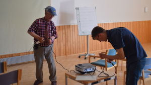 Thomas Backas hjälper Frank Lundgren med tekniken. två män med vid projektor