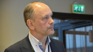 Arkivbild på Kjell Henrichson från Egentliga Finlands arbets- och näringsbyrå. Direktör Kjell Henrichson står på möte i vit kavaj och vit skjorta.