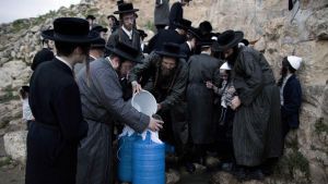 Ultrortodoxa judar tar vatten från en källa på Västbanken Ultraortodoxa judar samlar vatten från en källa utanför Jerusalem på Västbanken