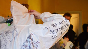 Sofia Wahlroos har skrivit på overallens ärm "Vi som aldrig varit i Österbotten o int tänker faa heller rf." - ett föreningsnamn från en populär skämtvideo. "vi som aldrig varit i österbotten o int tänker faa heller rf."