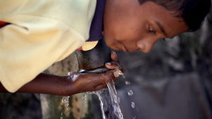 Indisk pojke dricker vatten ur en arsenikförgiftad brunn. Pojke dricker arsenikförgiftat vatten i byn Jayant Para i Indien