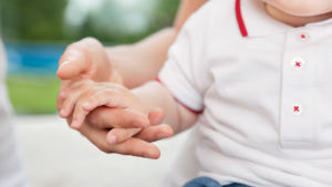 Ett litet barn håller sin förälder i handen.