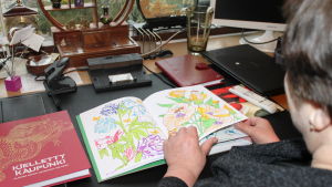 Nainen selaa tekemäänsä värityskirjaa.