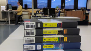 Kuvanauhat ovat tuttu näky Arkiston tietopalvelussa, vaikka suuri osa aineistosta on jo digitoitu. Kuvanauhoja Yle Arkiston tietopalvelussa, taustalla työntekijä.