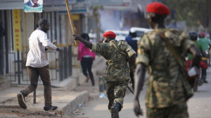 En militärpolis hotade en man med en pinne under Besigyes kampanjtåg i Kampala i måndags. polis hotar man med pinne