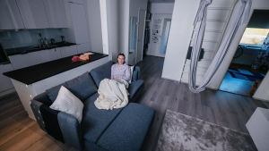 Long covidista kärsivä Jaana Saukko istuu kotonaan sohvalla.