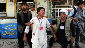 Män hjälper en av de skadade efter attentatet mot demonstrationen i Kabul 23.7.2016