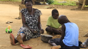 Francis mamma och ett par av hennes barnbarn skalar jordnötter. Det ska bli jordnötssmör. Francis mamma torterades under kriget av LRA-rebeller. en kvinna och två barn rensar jordnötter i norra Uganda