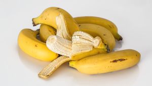 Kuvassa banaaneja, yksi kuorittu auki.