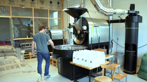 Juhani Haahti visar de två rostmaskinerna. Han rostar kaffe till restauranger och caféer med den större. Den mindre kafferostaren används för att rosta kaffe för dem som gjort beställningar via webbaffären. Juhani Haahti gå omkring i sitt lilla kafferosteri i S:t Karins.